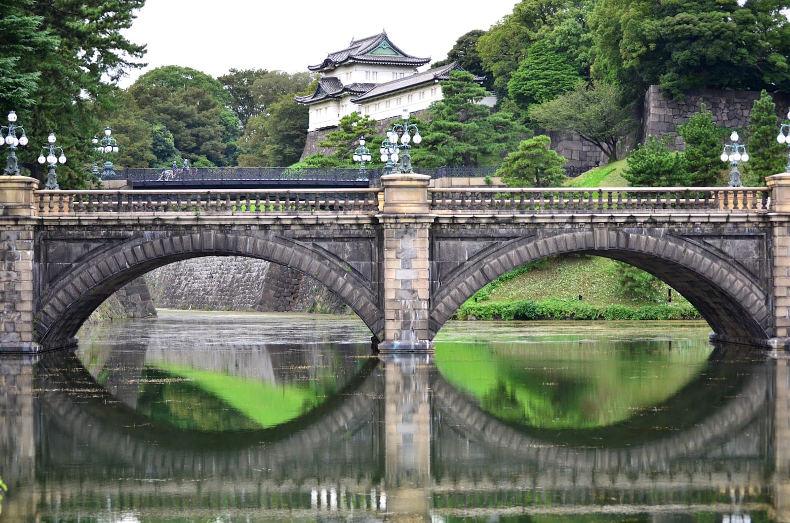 Un puente de piedra sobre el foso del Palacio Imperial, con una torre de vigía al fondo