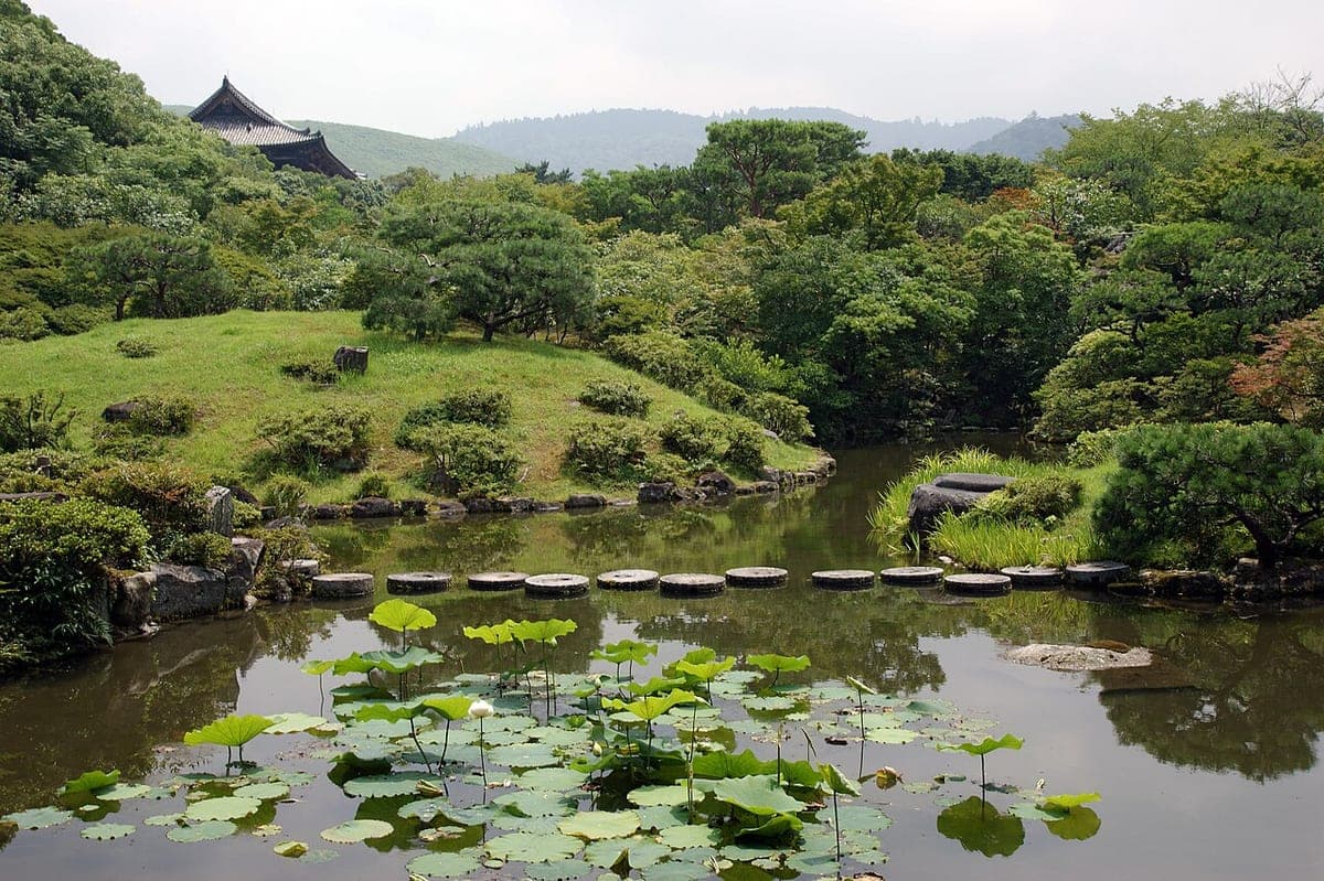 El estanque y las piedras de paso del Jardín Isuien con paisaje de montaña prestado